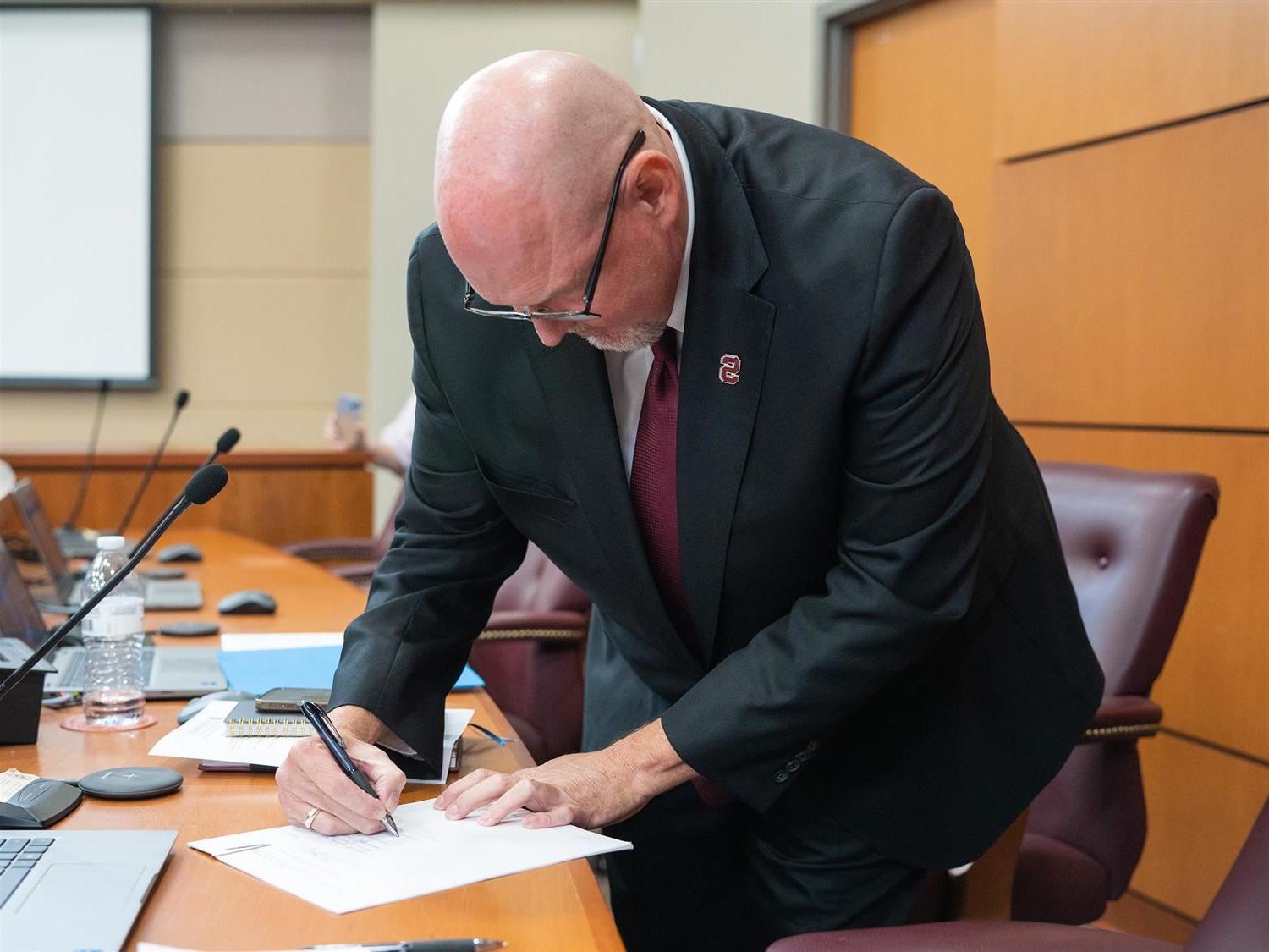  Dr. Thomas O'Neal signs his superintendent contract.